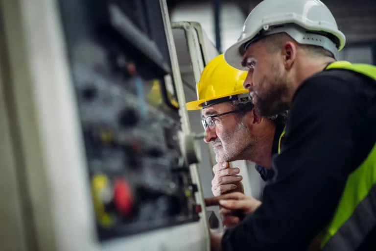 Een team van ingenieurs dat aan een machine op de werkvloer werkt