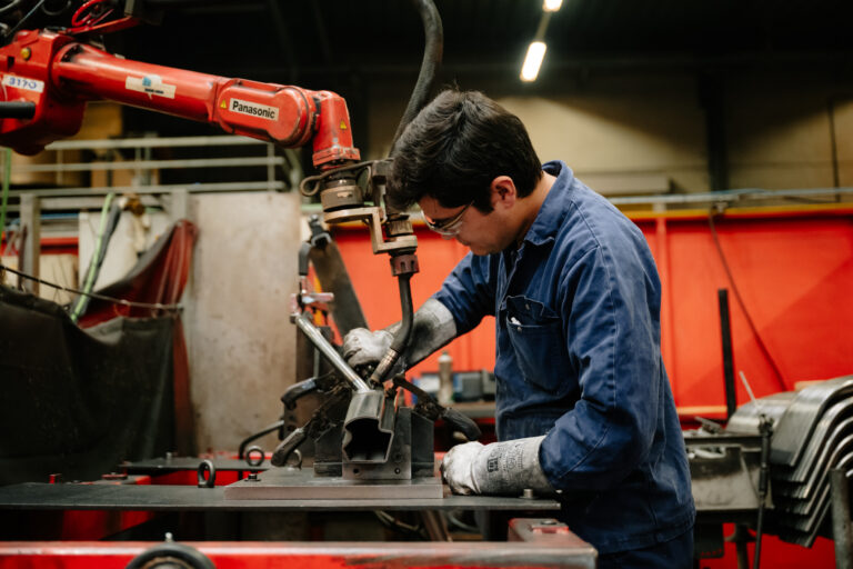 Een operator die een lasrobot op de werkvloer installeert